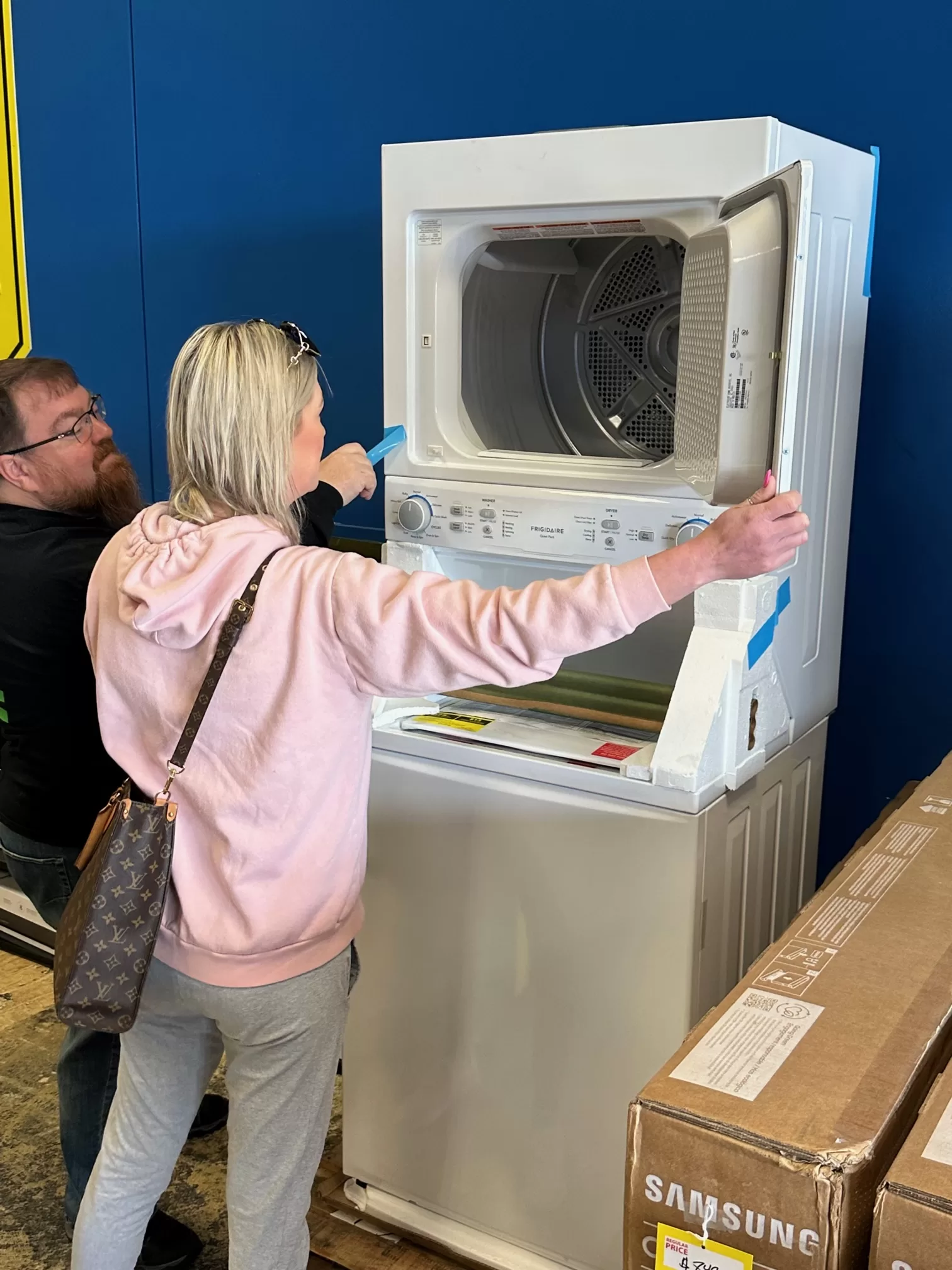Customers Inspecting an Upright Washer/Dryer Appliance at Our TV, Appliance and Bin Store - The Attic of the Quad Cities